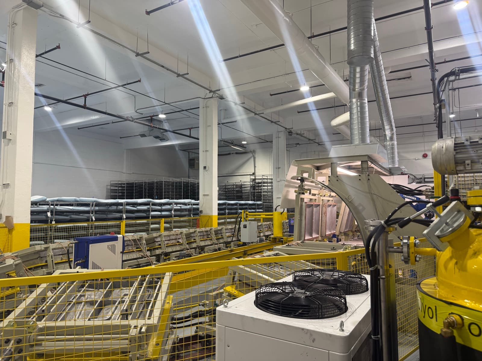 Maple Sleep production floor with foam molding line and racks of curing pillows.