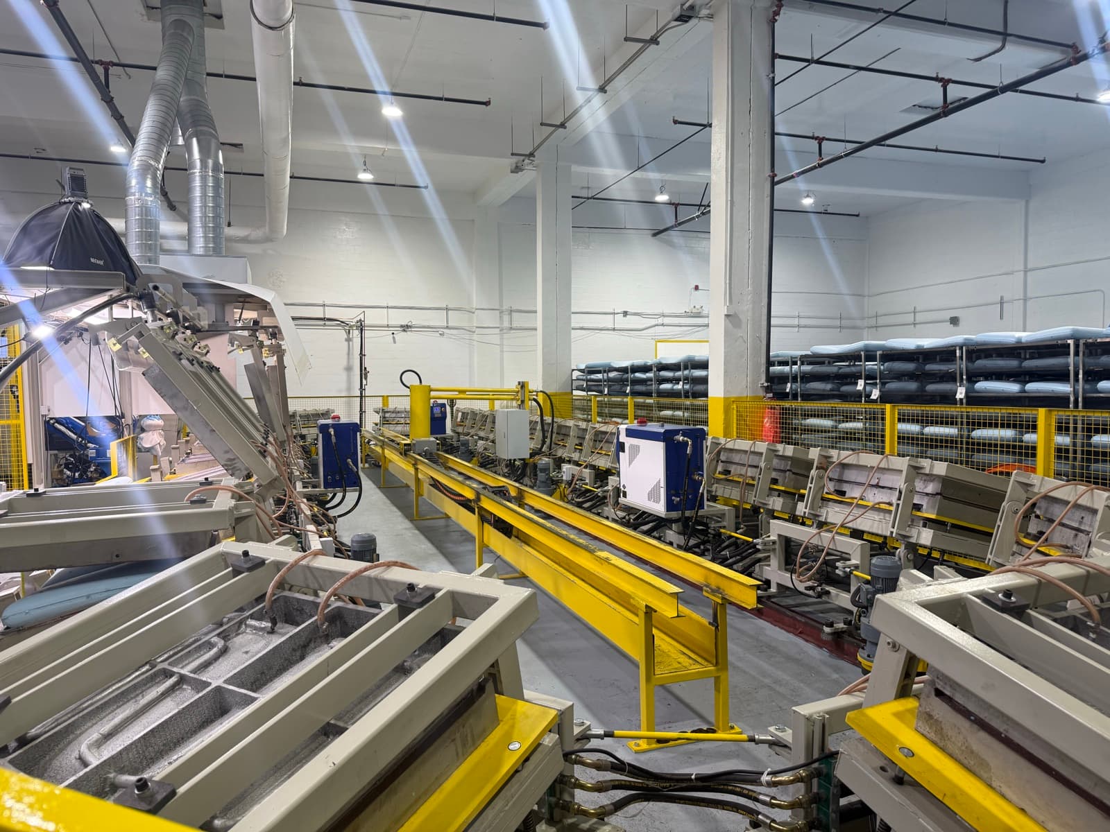 Active foam molding conveyor at the Saint-Jean-sur-Richelieu plant with curing racks visible behind safety fencing.